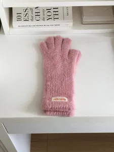 Detail view of pink fuzzy winter touchscreen gloves, soft plush texture close-up on desk.