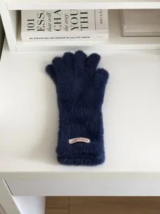 Detailed close-up shot of cozy dark blue plush winter gloves with a cute cuff label.