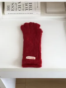 Red plush winter gloves detail shot, soft fuzzy texture, warm casual daily wear accessory.