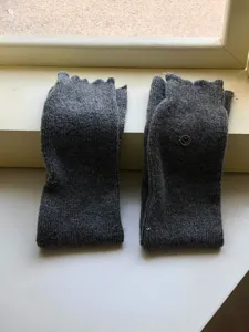 Detail van de grijze wollen gebreide beenwarmers met zachte textuur voor de winter.