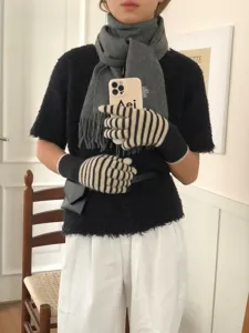 Detailaufnahme der warmen Strickhandschuhe mit Streifen und grauen Winterschal Kombination.