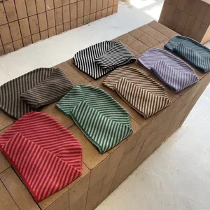 Close-up detail of multi-color striped knitted hooded scarves showing soft texture and patterns.
