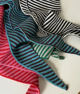 Close-up detail shot of colorful striped knitted scarf shawl, soft warm knit texture fabric.