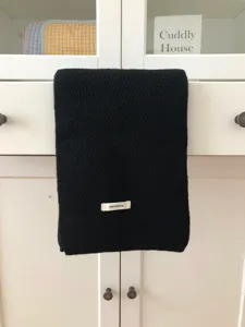 Black wool scarf detail showcasing soft knitted texture and cozy premium winter warmth.