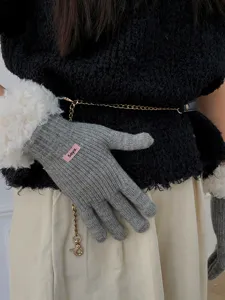 Grey knit winter gloves detail shot showing soft texture, cozy warmth, and cute pink label.
