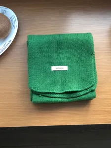 Green wool scarf detail view, showing soft knitted texture and warm winter material.