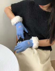 Detail view of blue winter knit gloves featuring soft white plush cuffs and cozy wool design.