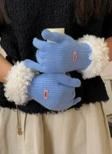 Detailed shot of winter warm knitted gloves in blue with plush fuzzy cuffs and small tag.