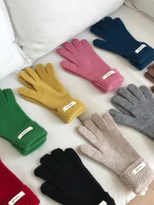 Vista detallada de coloridos guantes de invierno de lana tejida sobre fondo blanco suave.