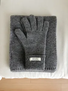 Vista detallada de guantes y bufanda de punto de lana gris con textura suave y cálida.