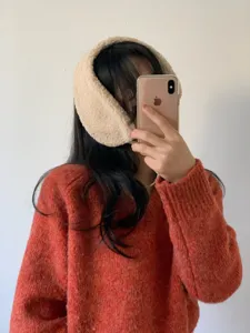 Fluffy beige winter earmuffs detail shot, cozy fleece ear warmer accessory for cold weather.