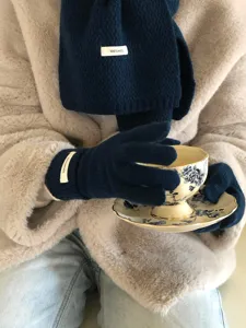 Guantes de punto de lana azul oscuro y bufanda en detalle, primer plano accesorio de invierno.