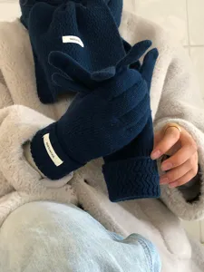 Primer plano detallado de guantes y bufanda de lana tejida de invierno calientes en color azul.