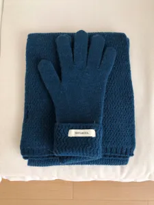 Detalle en primer plano de guantes de punto de lana cálida y bufanda en azul oscuro.