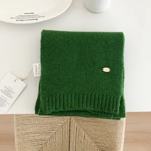 Vista detallada de bufanda de punto de lana verde lisa, con textura suave y estilo acogedor.