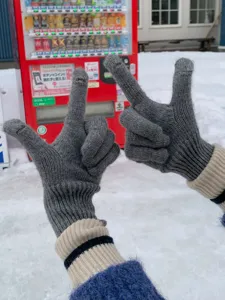 Grijs gebreide touchscreen handschoenen detail met vingeringang en ribboord in wintersneeuw.