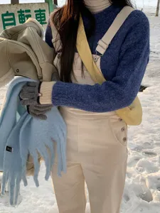 Close-up van winterse gebreide handschoenen en sjaal in de sneeuw, gezellige koude stijl.