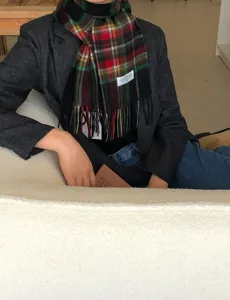 Gros plan d'une écharpe d'hiver en laine à carreaux rouges portée avec une veste.