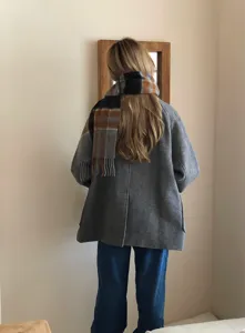 Gedetailleerd shot van een klassieke geruite sjaal met grijze jas, ideaal voor koude dagen.