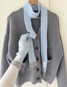 Gros plan detaille foularde maille bleu clair et gants tactiles, texture hivernale douce.