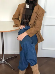 Gedetailleerde opname van een stijlvolle bruine geruite wollen sjaal gedragen met blazer.