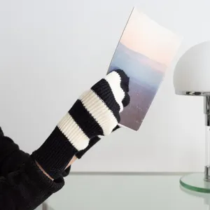 Gros plan de gants tricotés rayés chauds d'hiver en noir et blanc, mode unisexe confortable.