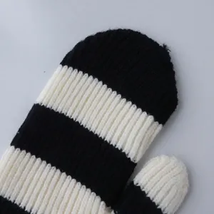 Gros plan de mitaines d'hiver tricotées à rayures noires et blanches pour un look chaud.