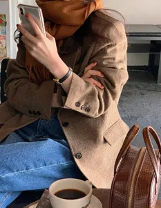 Vista detallada de una cómoda bufanda de lana con flecos combinada con un elegante blazer de otoño.
