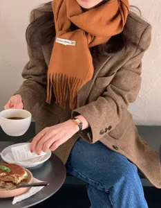 Primer plano detalle de suave bufanda de lana marrón con flecos en estilo acogedor.