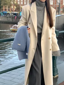 Detailed view of cozy wool scarf in haze blue worn with winter coat and turtleneck sweater.