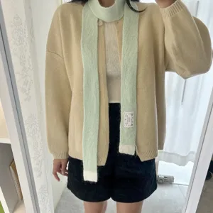 Écharpe longue en tricot vert pastel douillette avec pointes contrastées blanches.