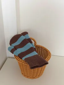 Vue rapprochée détaillée de mitones en tricot rayées marron et bleu clair dans panier.