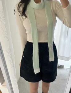 Vue détaillée d'une écharpe en tricot vert clair, montrant la texture et le style d'automne.