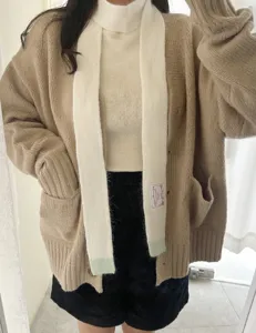 Vue détaillée d'écharpe et gilet beige, tissu tricoté doux pour l'hiver chaleureux.