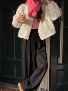 Cozy winter outfit featuring white fleece jacket, pink wool scarf, and black trousers.
