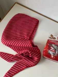 Red pink striped knitted balaclava hooded scarf warm winter accessory detail shot.