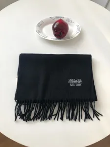 Nahaufnahme des schwarzen Wollschals mit stilvoller weißer Stickerei und Fransen.
