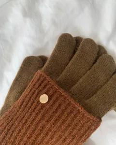 Detailed view of women's warm knit colorblock gloves with stylish contrast design and button.
