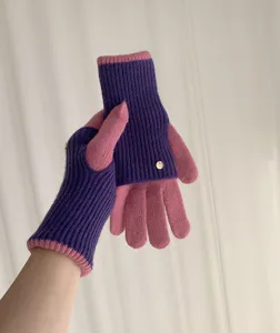 Knitted color-block gloves detail view showcasing soft texture and delicate metal button decoration.