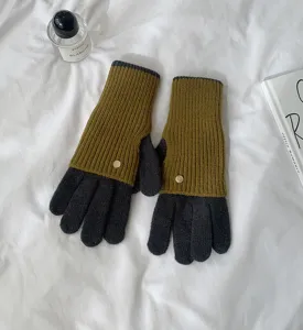 Detail view of colorblock knit gloves on white fabric with minimalist props for winter warmth.