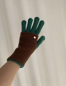 Close-up view of color-block knitted gloves showcasing the ribbed cuff and button detail.