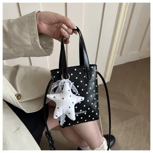 Primer plano detallado de un mini bolso bandolera de lunares blancos y negros con colgante estrella.