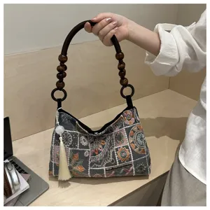 Dettaglio di una borsa a mano ricamata in stile cinese con manico di perle di legno e nappa.
