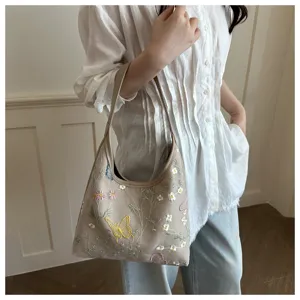Vista de cerca del elegante bolso de hombro bordado con delicados detalles de mariposas y flores.