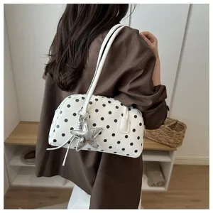 White black polka dot shoulder bag with silver star charm, detail view of stylish handbag.