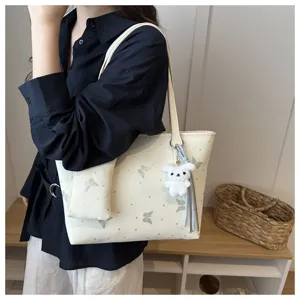 Vista dettagliata della borsa tote beige elegante con stampa farfalla e ciondolo cucciolo.