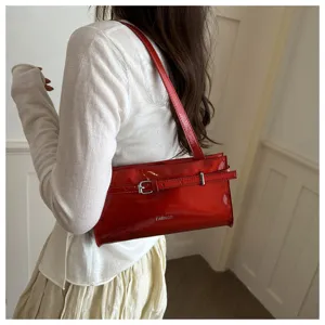 Chic red patent leather shoulder bag for women, stylish armpit handbag with trendy buckle.