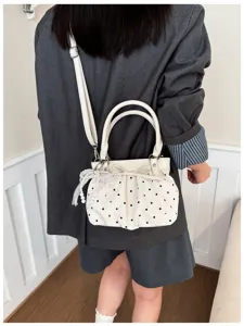 Primo piano della borsa a spalla bianca a pois con delicate perle e grazioso fiocco.