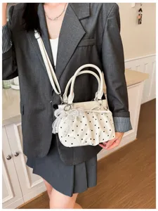 Detail shot of women's pleated polka dot underarm shoulder bag with elegant pearl bow charm.