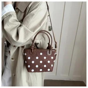 Brown suede polka dot handbag with top handle and crossbody strap for daily commute and casual use.